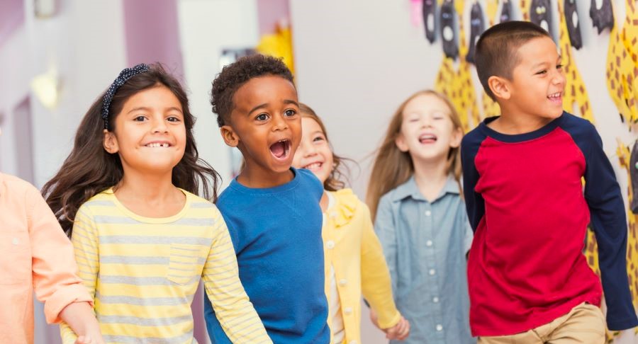 Young children smiling with friends at school dance.