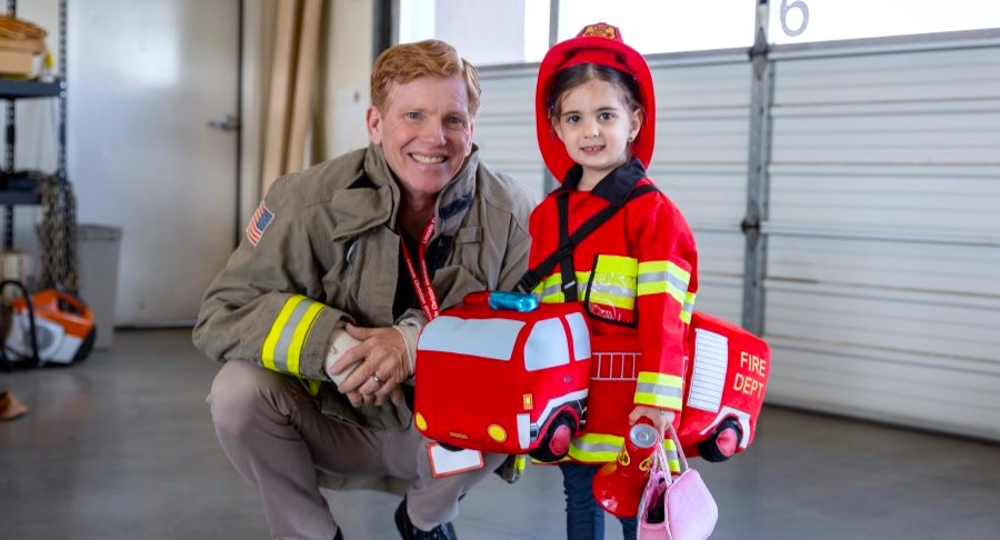 Child dressed up as a firerfighter and fireman posed for photo.