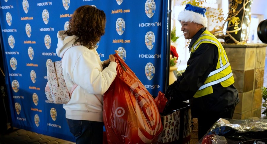 Woman donating a bag of jackets for Henderson's Coats for Kids drive.