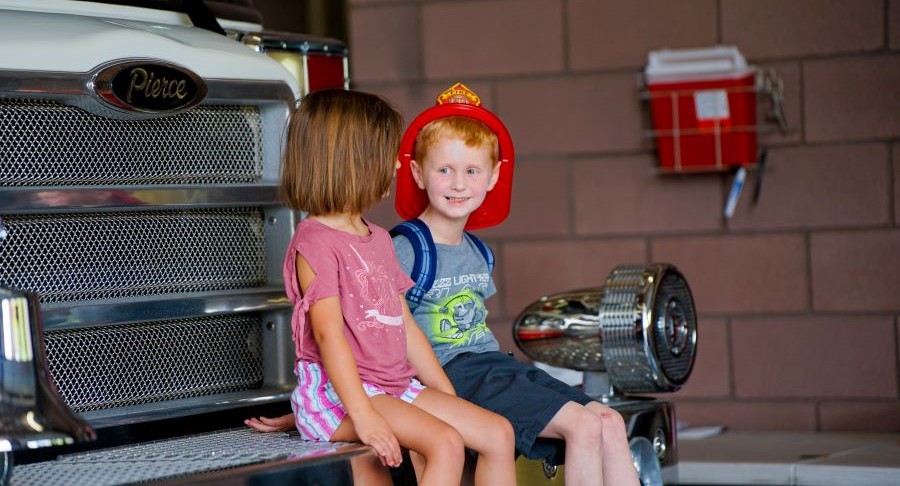 Two kids sitting on a firetruck at a Henderson Open House