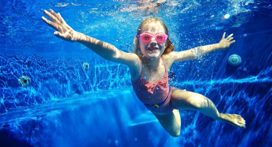 Little girls swimming under water in a pool.