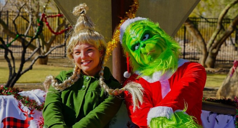 The Grinch and Cindy Lou Who sitting on a bench.