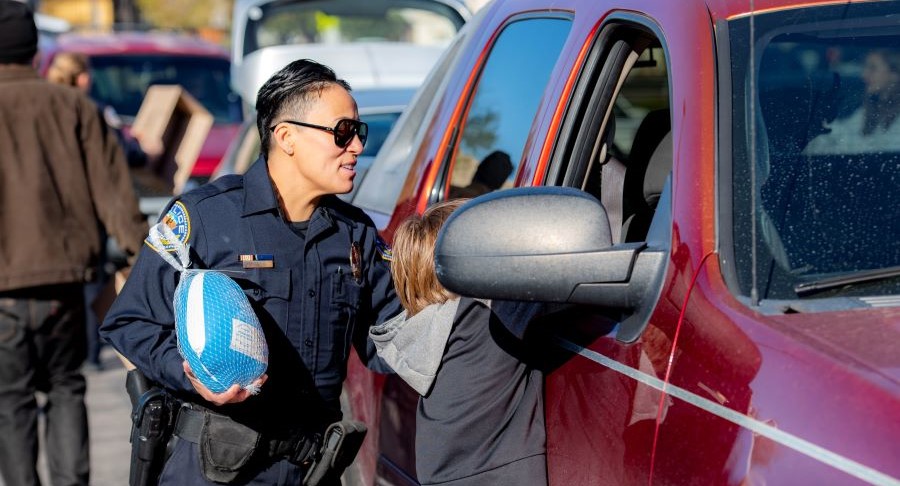 HPD Officer and young boy hand resident in a truck a turkey.